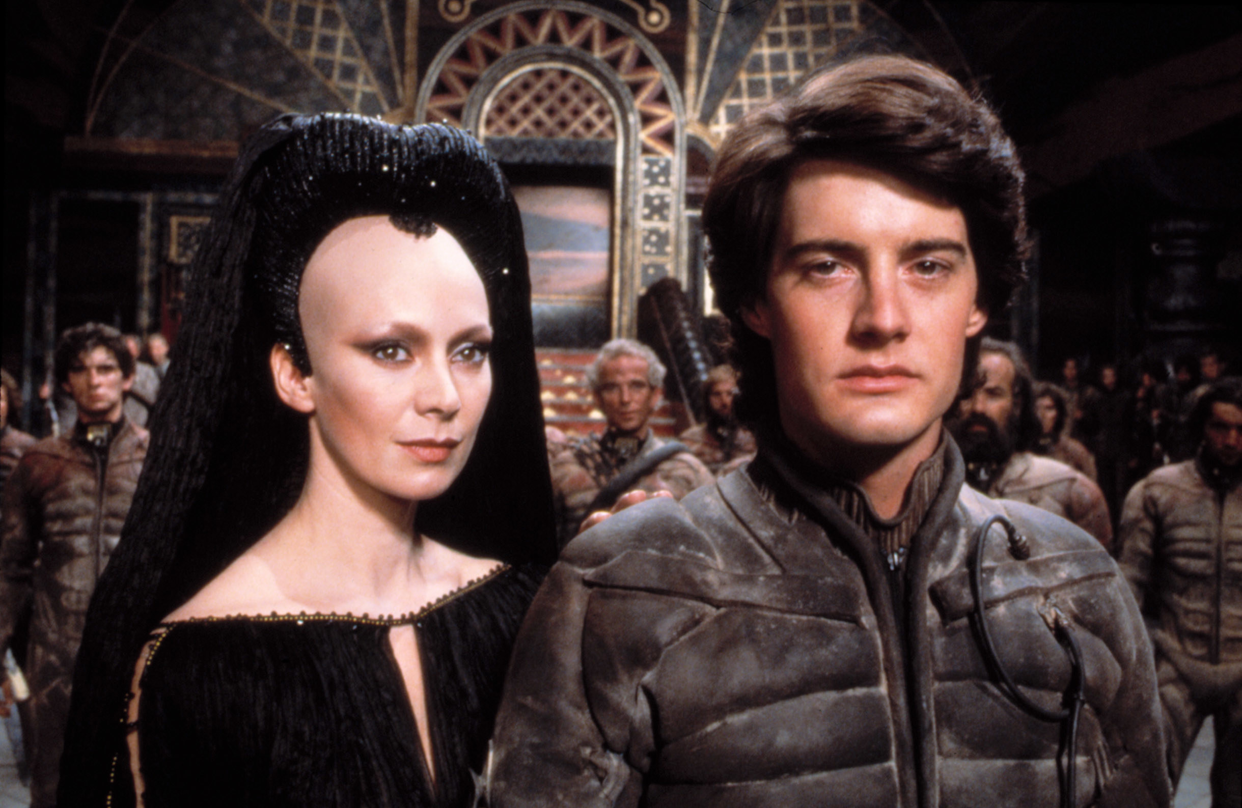 A woman and a man in futuristic clothing stand close