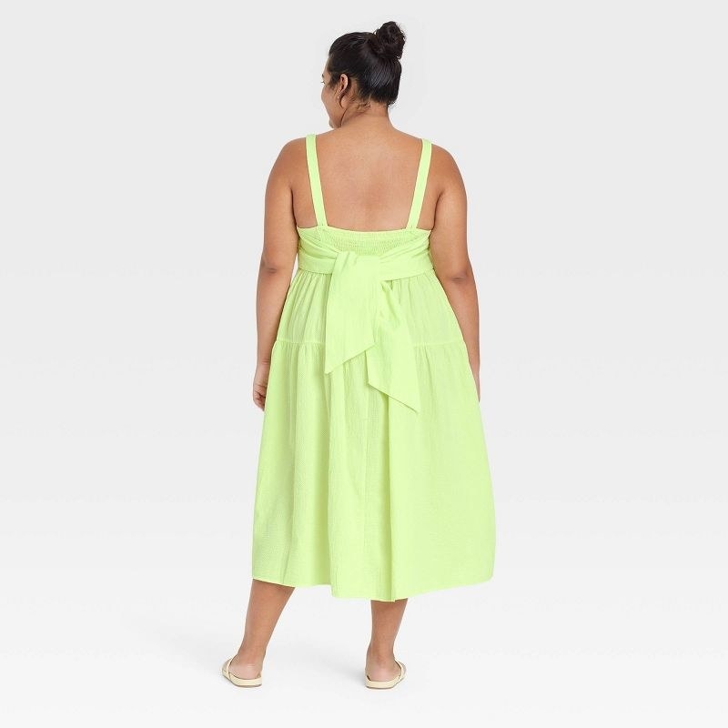 the dress in neon yellow shown from the back with a bow