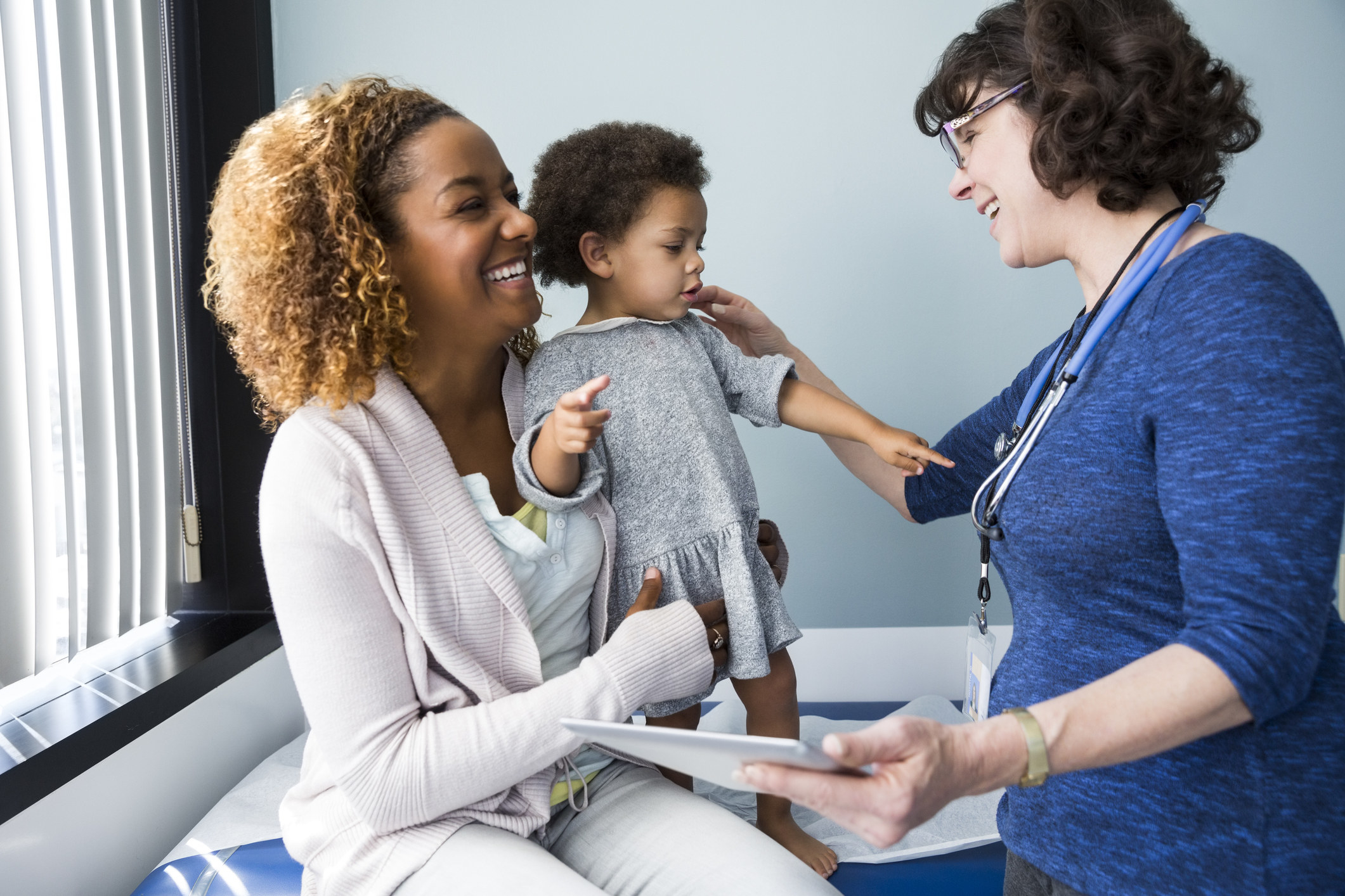 A mother with her infant daughter speaking to a nurse at the doctor&#x27;s office