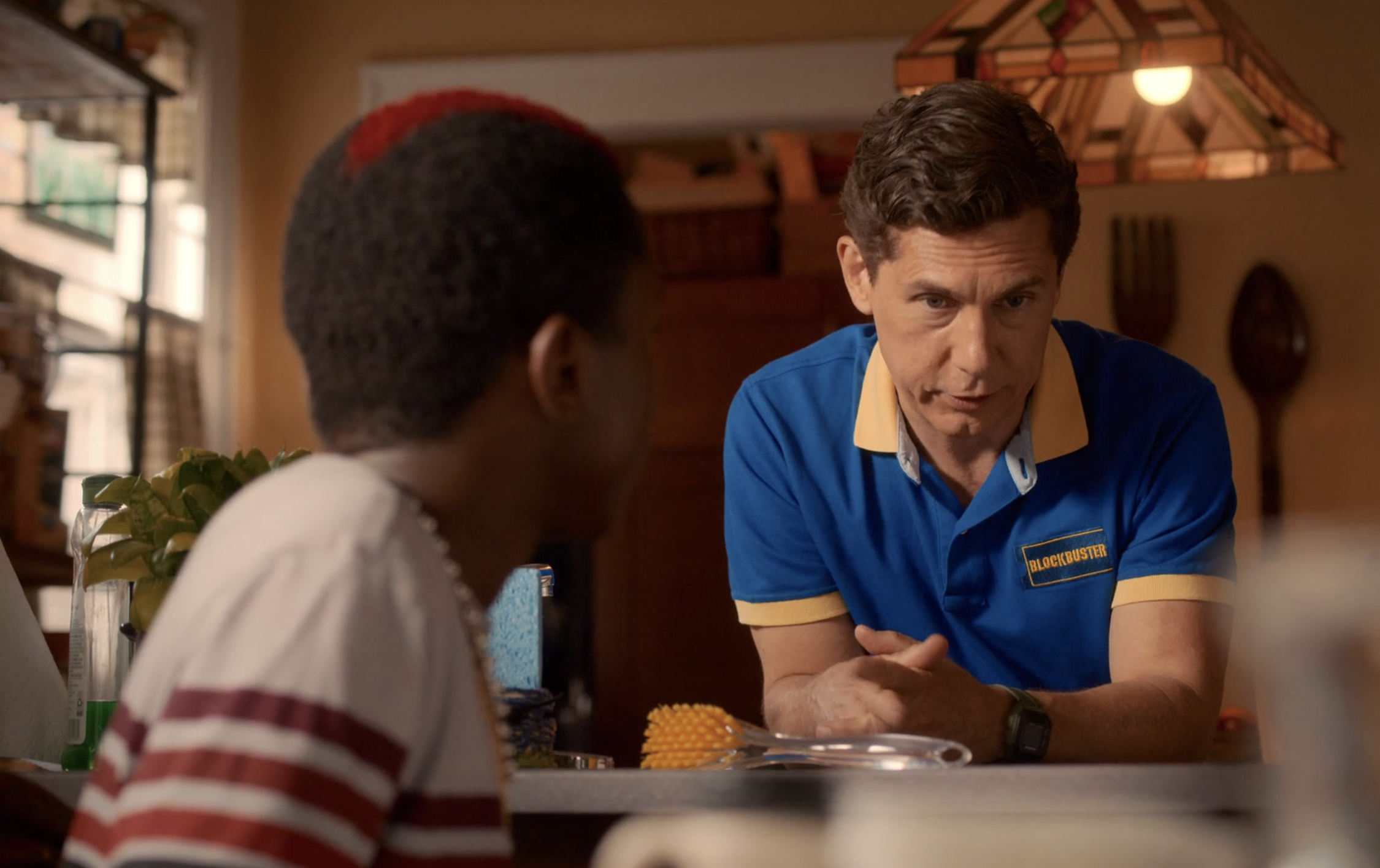 Man in a Blockbuster uniform leading on a table