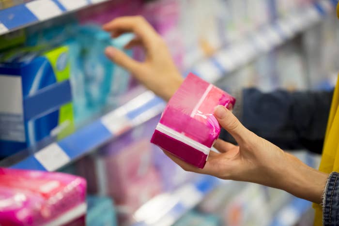 woman is choosing between pad and tampon in the store
