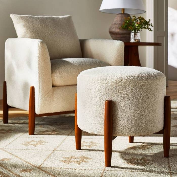 a round ottoman in cream and brown on a rug in a living room