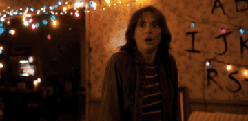 joyce byers from stranger things looking scared at flashing lights in home