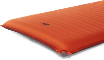 the corner of an inflated orange sleeping pad, showing off the air nozzle