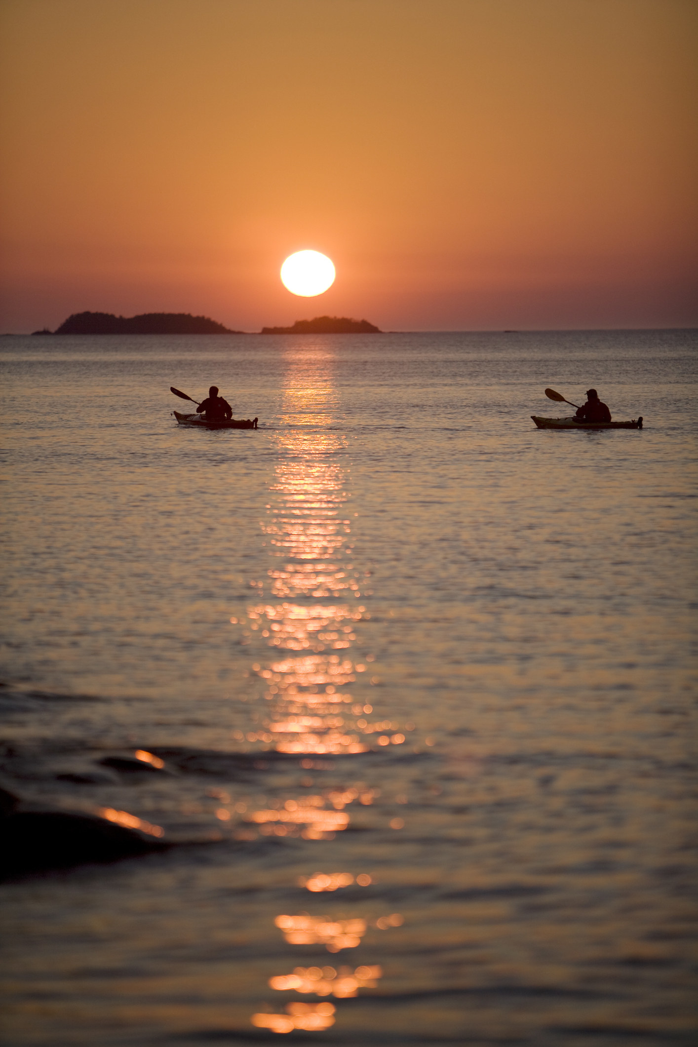 Kayakers paddling into the the sunrise at Isle Royale.