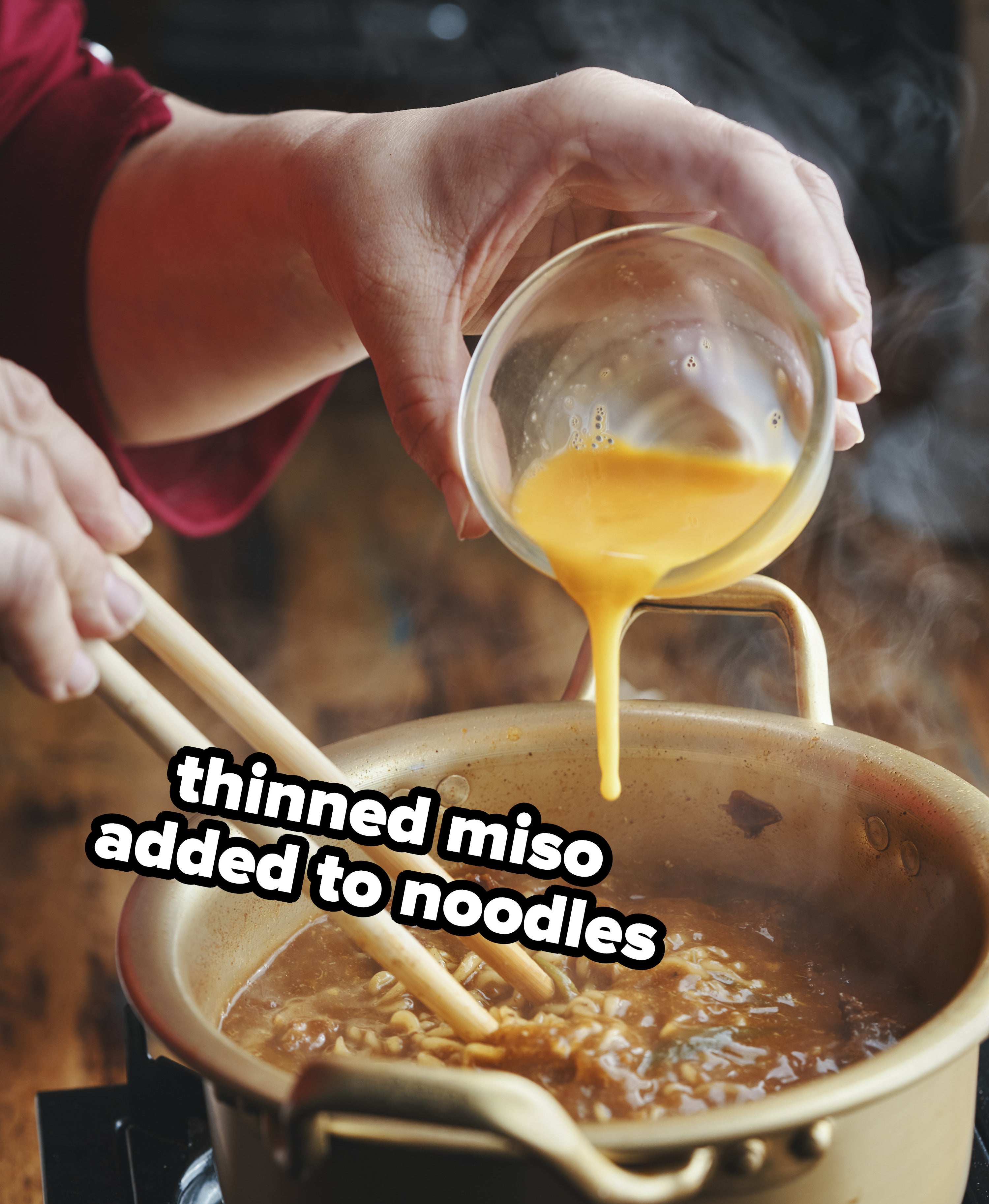 miso being poured into a pot of noodles