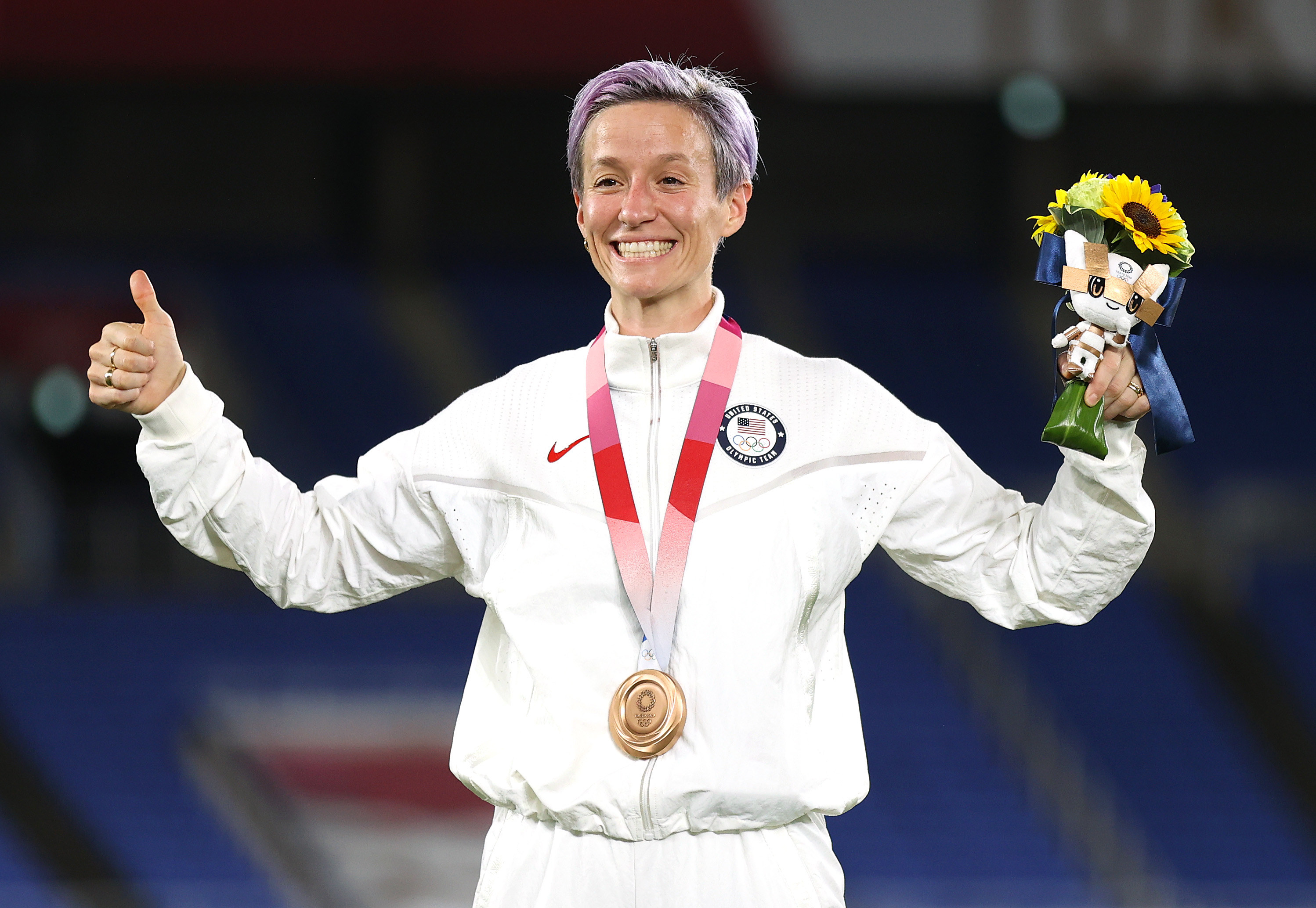 Megan Rapinoe gives a thumbs up as she wears a medal around her neck