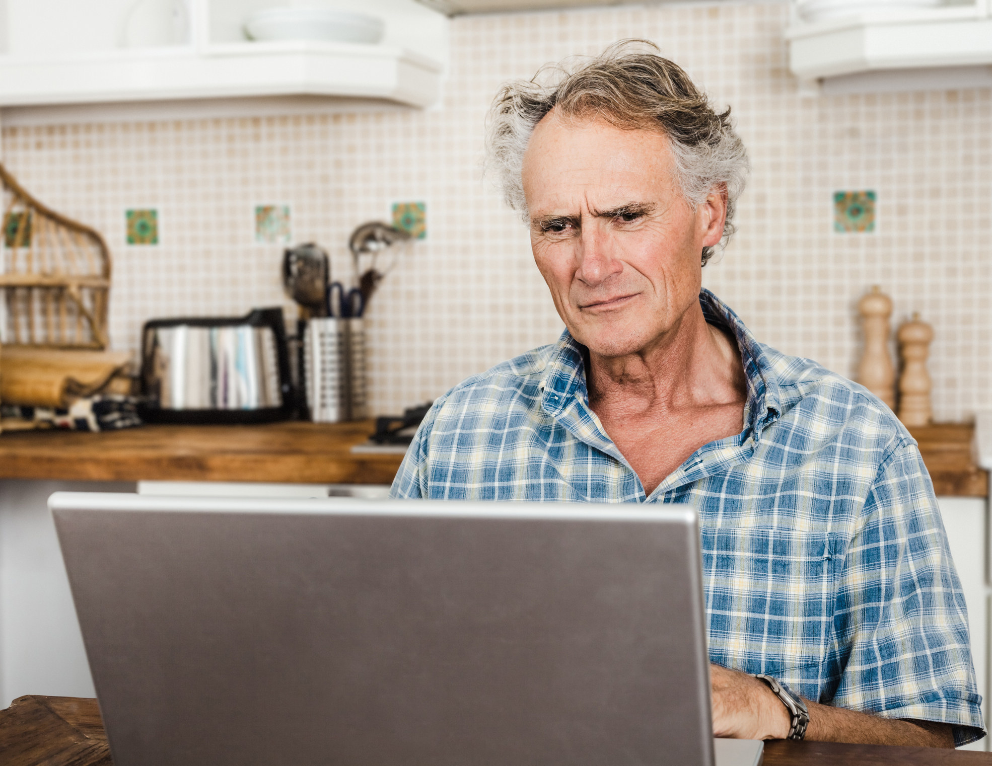 an older person looking confused at a laptop
