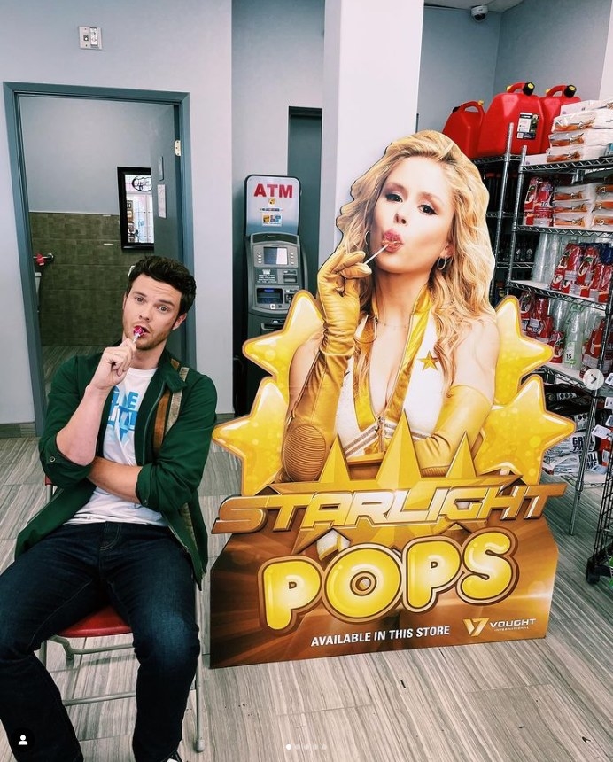 Jack Quaid sucks a lollipop in front of an advertisement cut out of Starlight