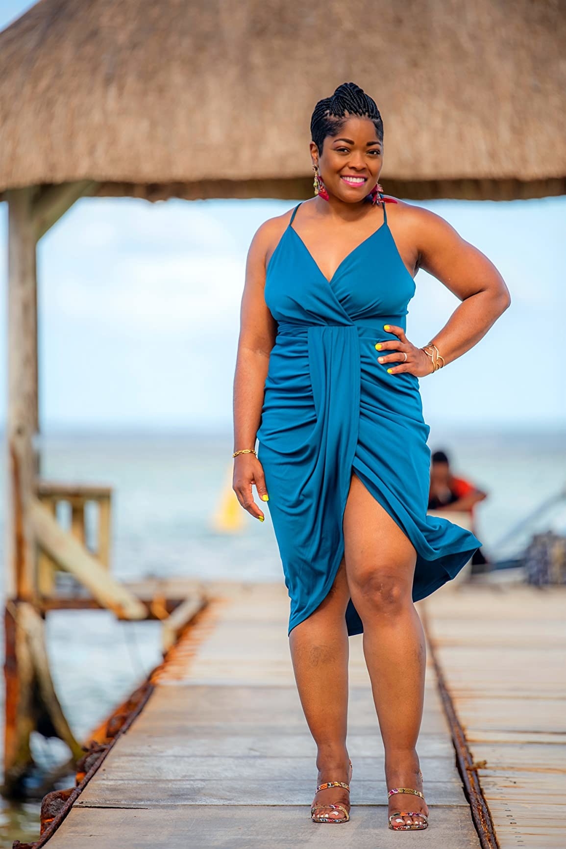 a reviewer wearing the dress in blue on a tropical ocean pier