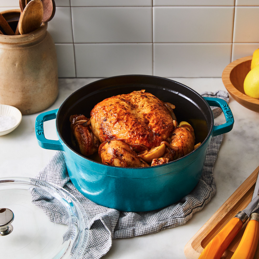 a blue cast iron cocotte with chicken in it