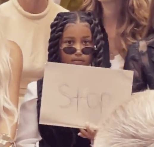 North West holding a sign that says "Stop"