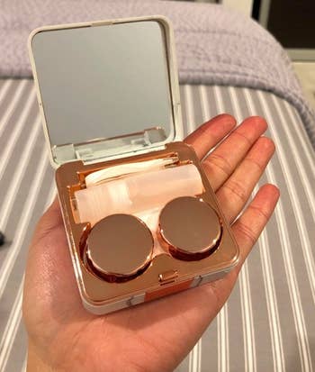 reviewer holding the contact lens case open to show the mirror and room for contacts, solution, and tweezers 