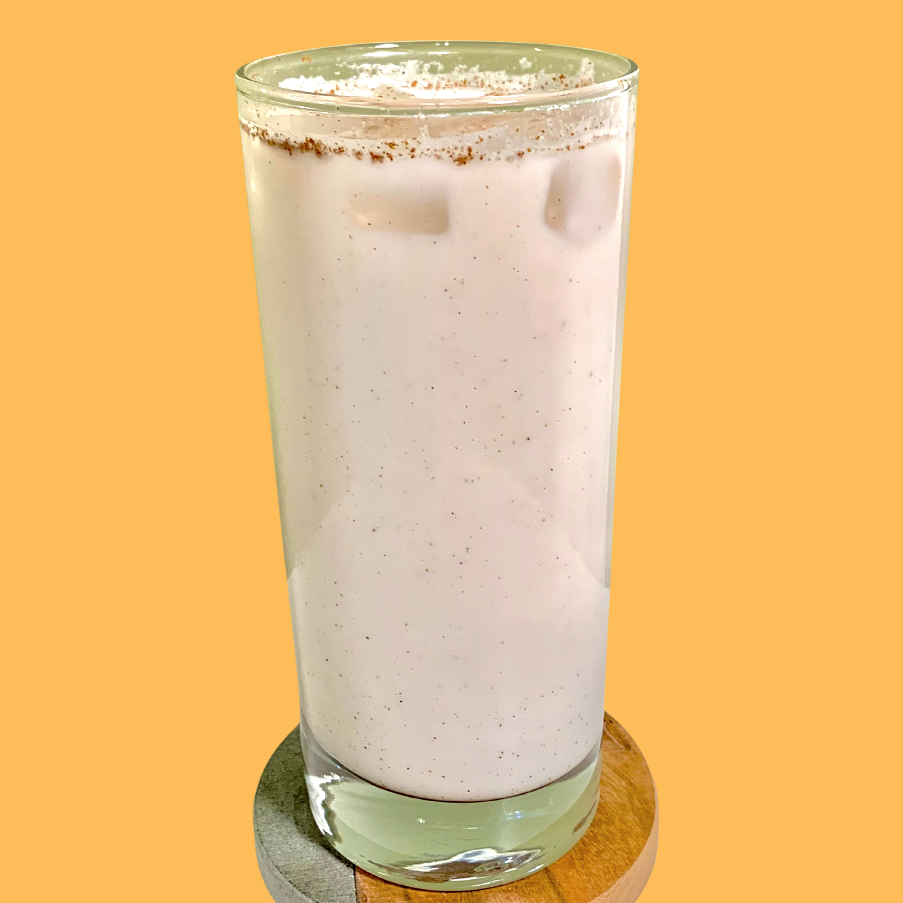 tall glass of the drink with cinnamon and nutmeg floating throughout