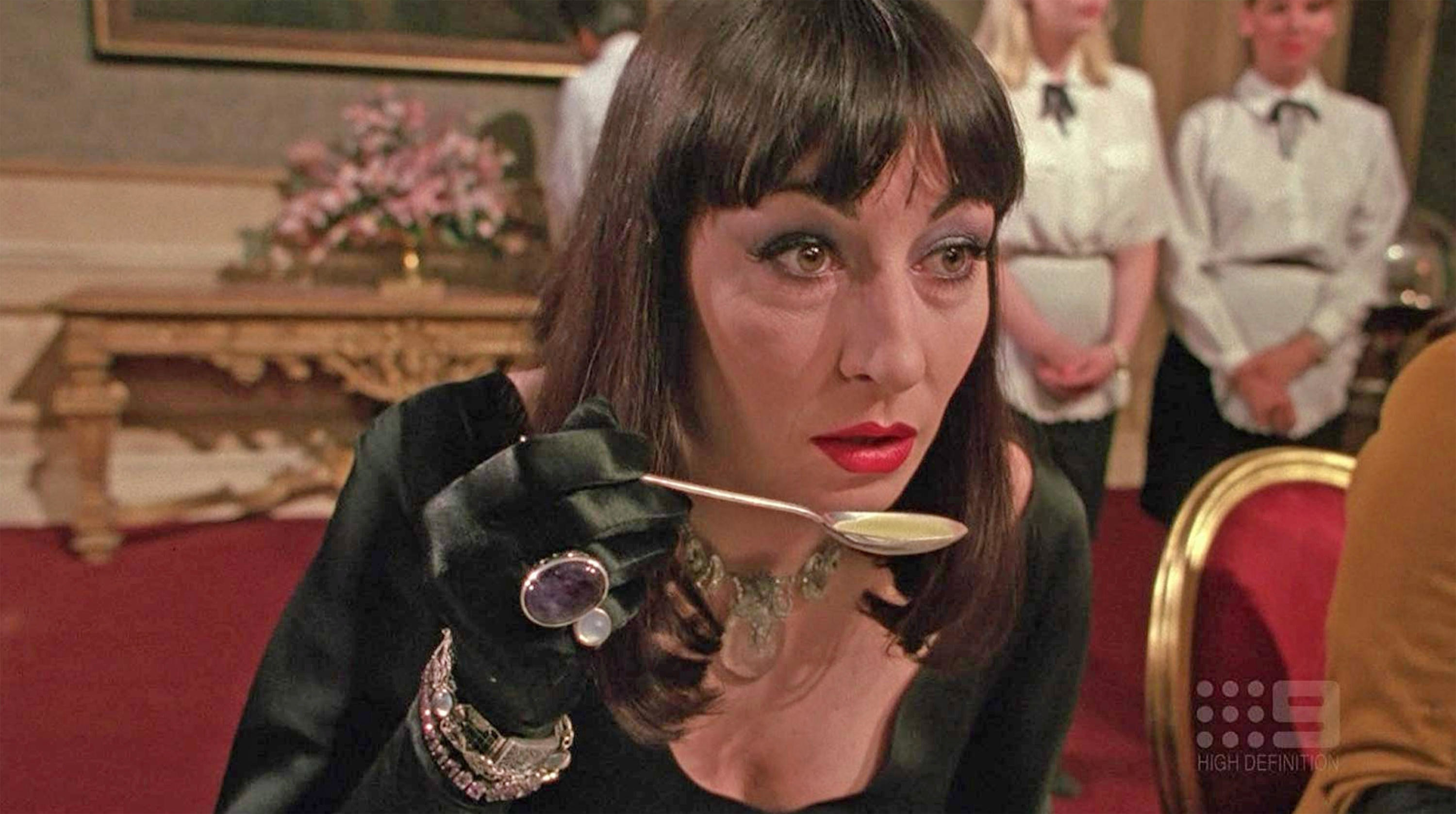 anjelica huston holding a spoon and wearing costume jewelry in the witches