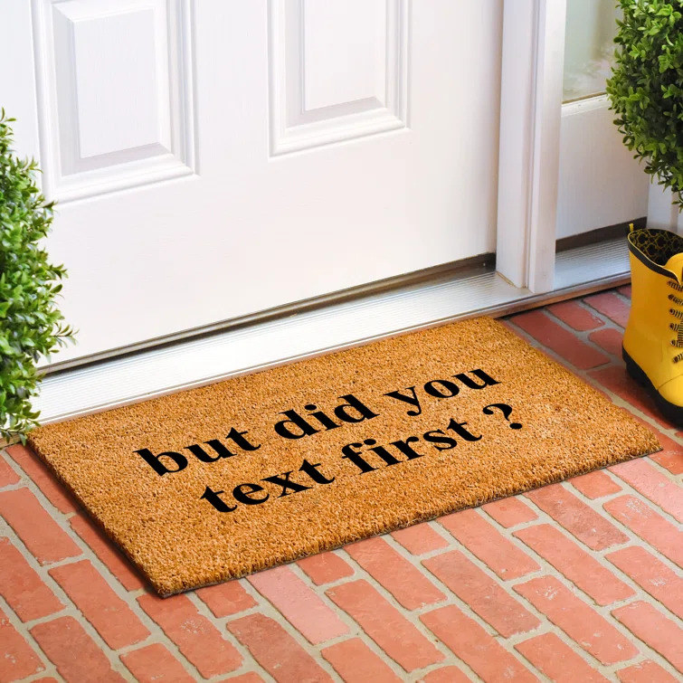 Brown doormat that reads, &quot;But did you text first?&quot; placed outside door on brick porch