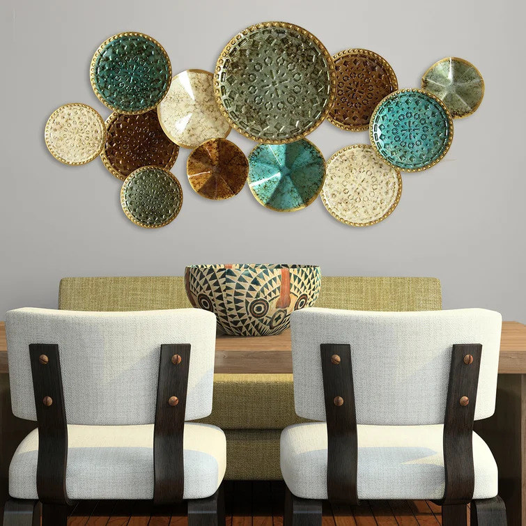 Multicolored plates mounted on wall above table and chairs