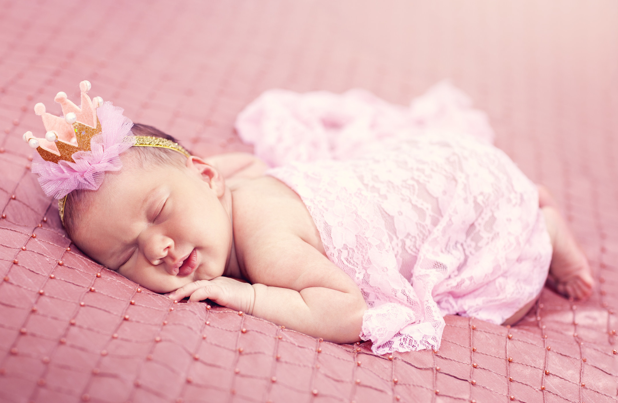 A baby dressed like a princess sleeping on a bed