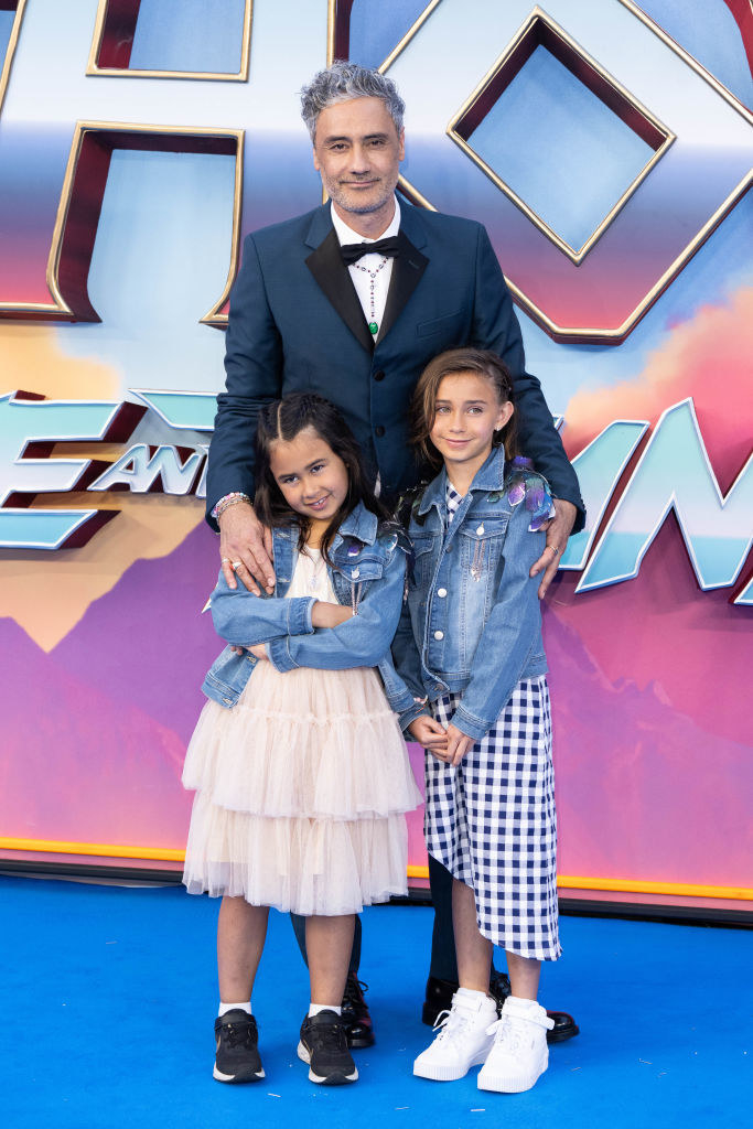 wearing matching denim jackets, Taika&#x27;s two little girls pose on the red carpet with his arms around them