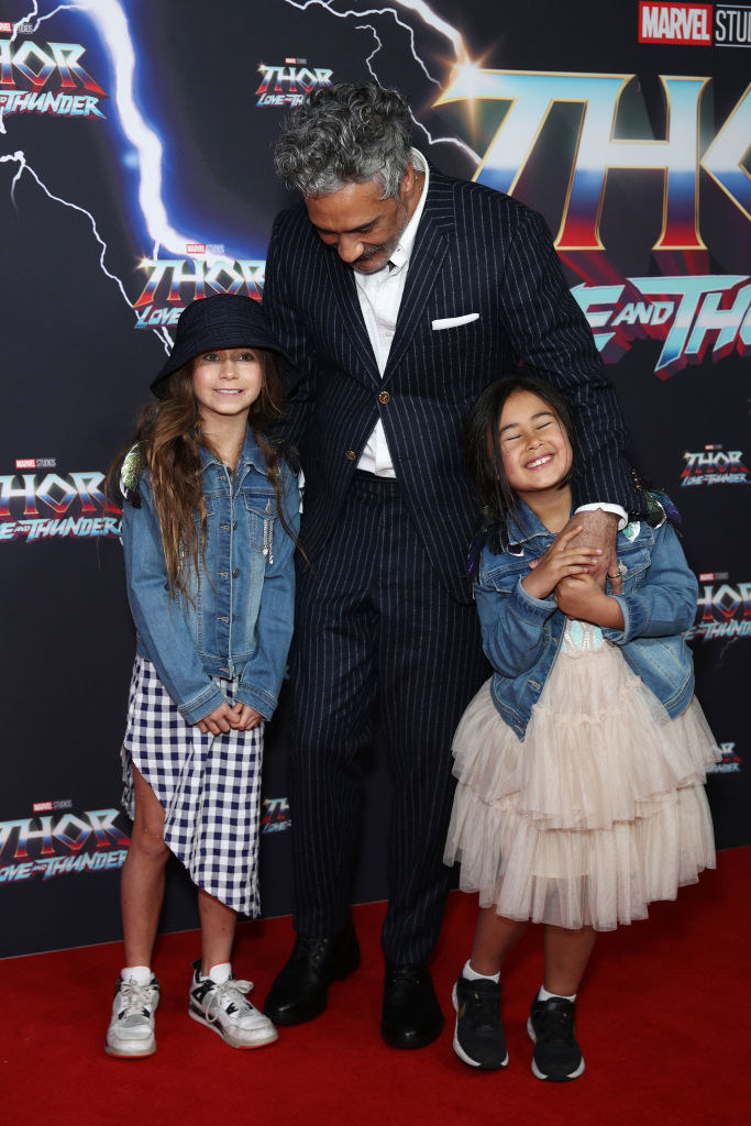 at the premiere, Matewa and Te hold their dad's hands and cuddle against him on the red carpet