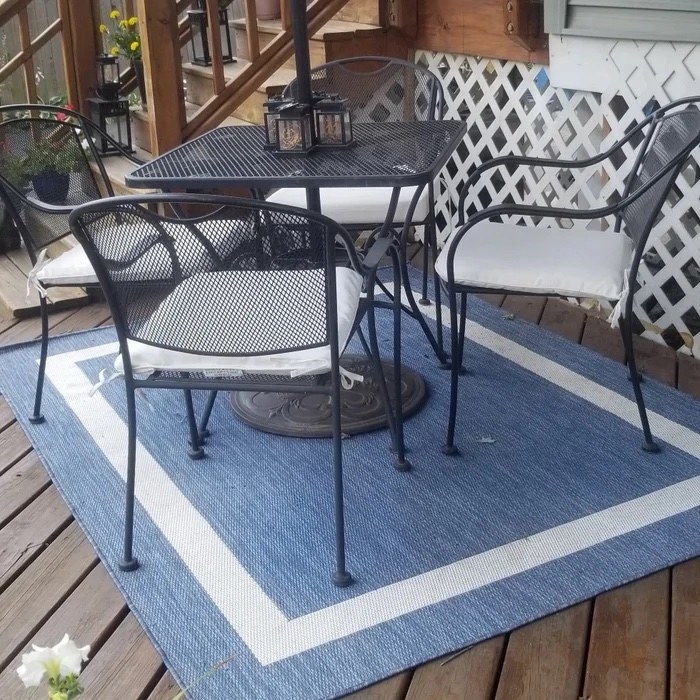 A reviewer&#x27;s  blue and white rug with black patio furniture