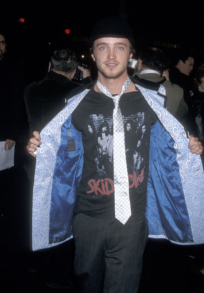 Aaron holding a coat open to show a Skid Row T-shirt and tie