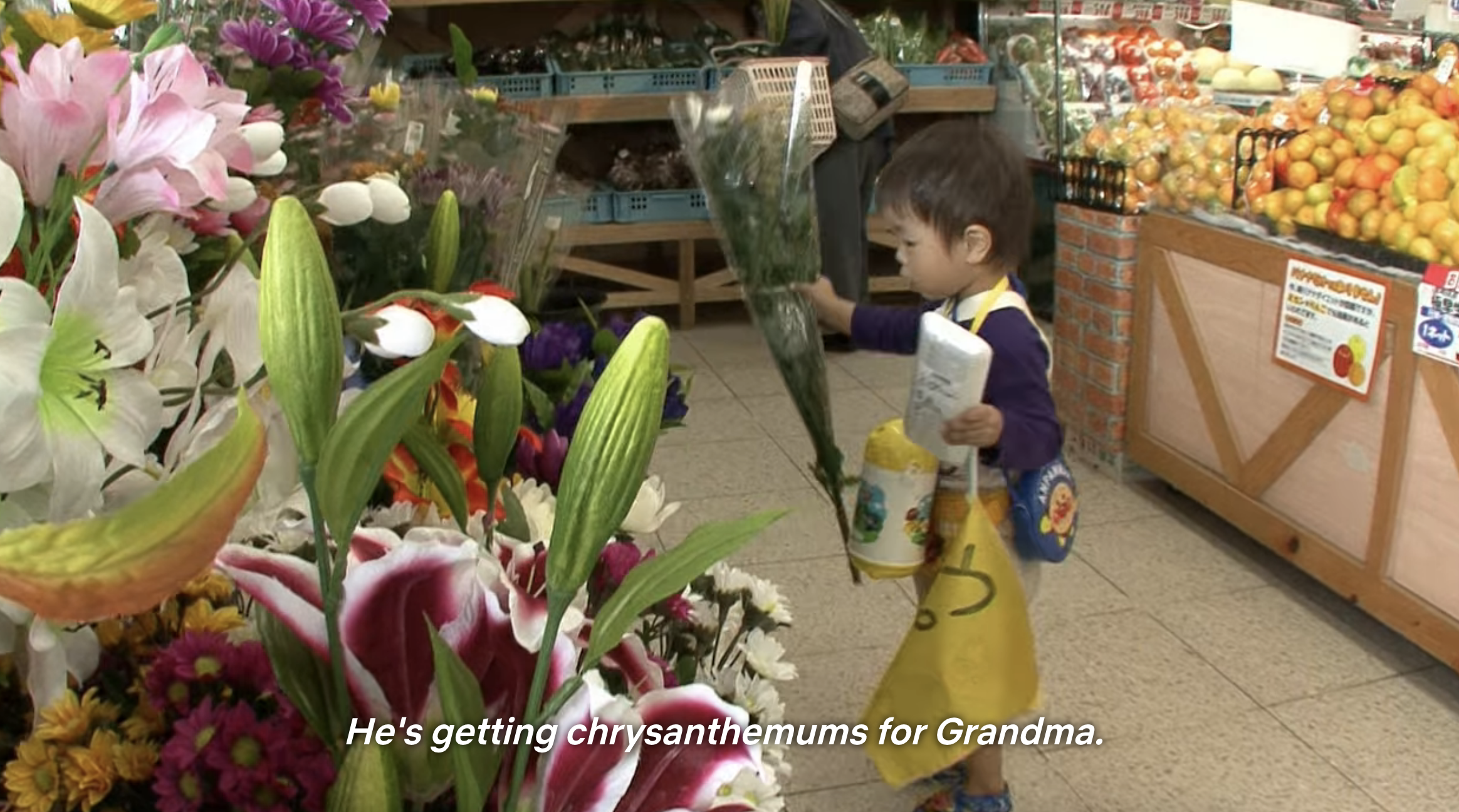 a very young child picking out flowers in a grocery store
