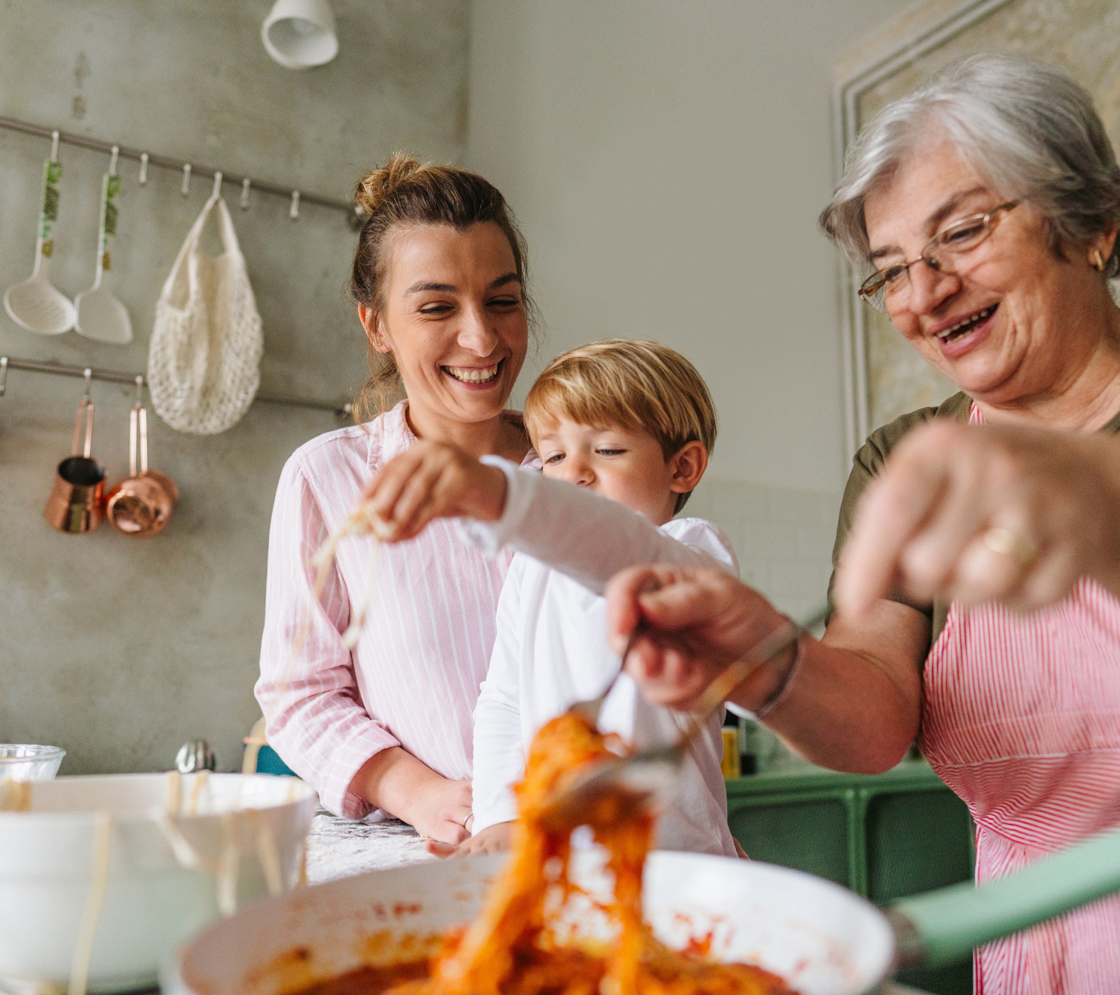 a family in a kitchen preparing spaghetti