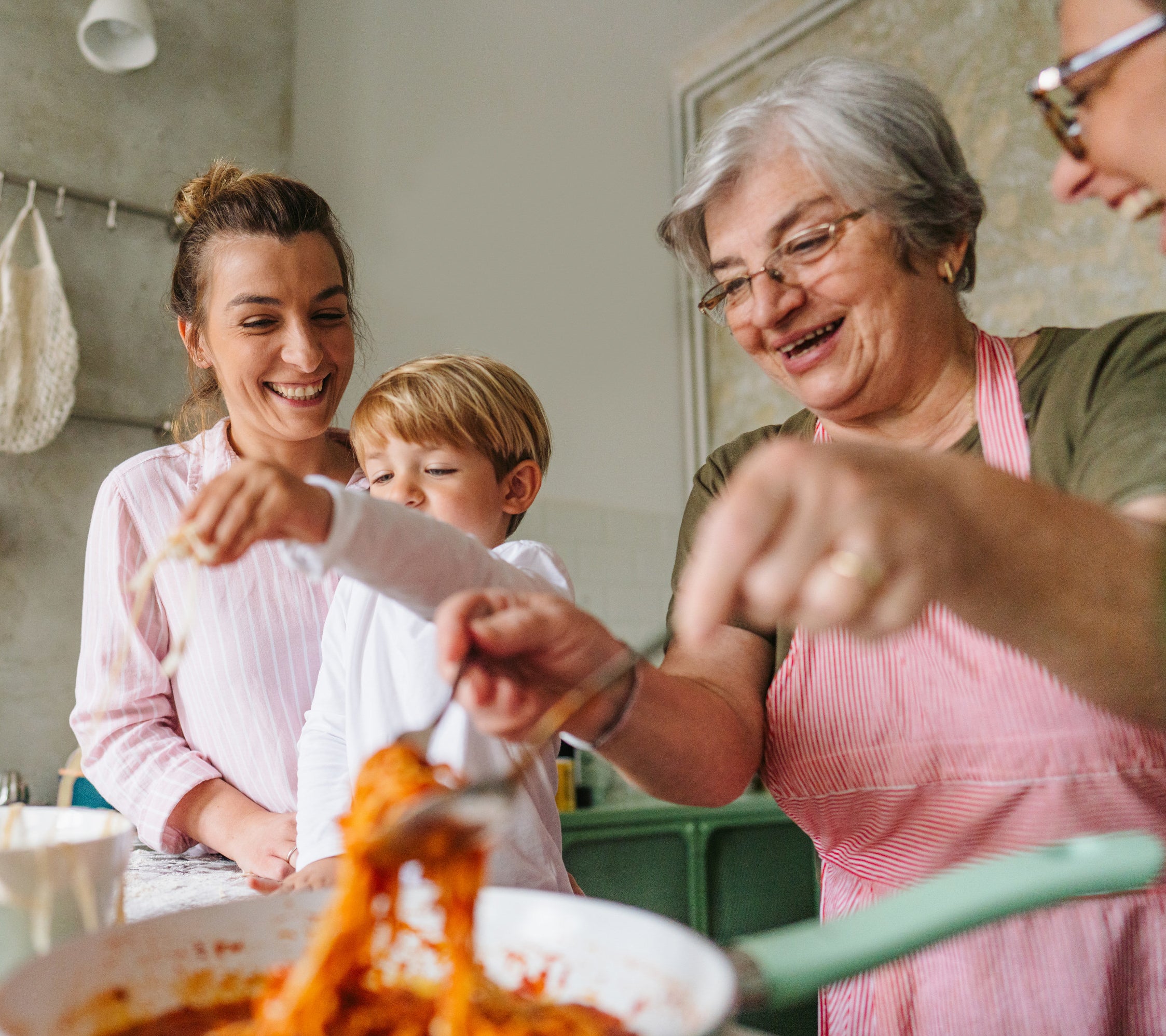a family in a kitchen preparing spaghetti