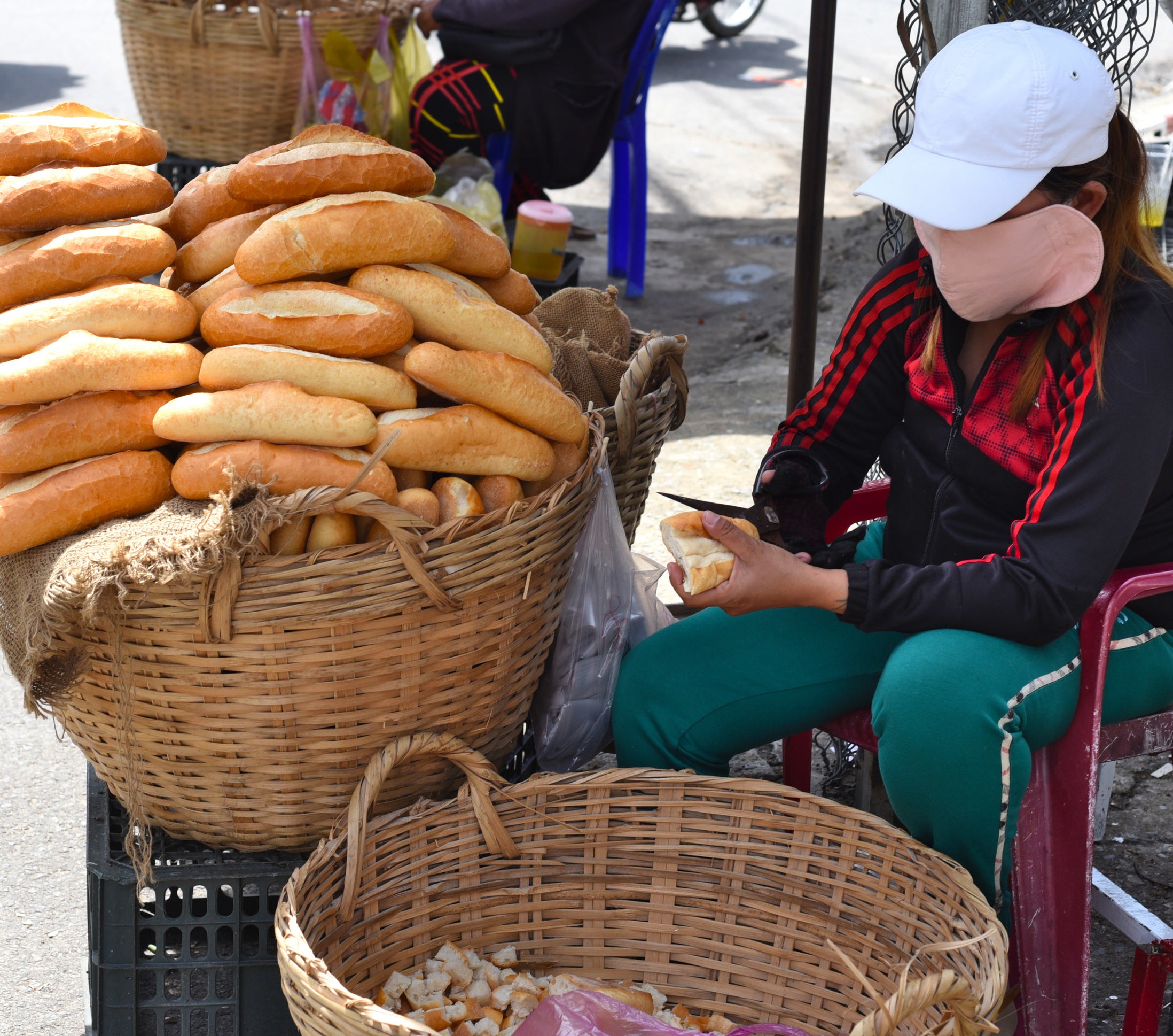 a person sitting by a basket of baguettes