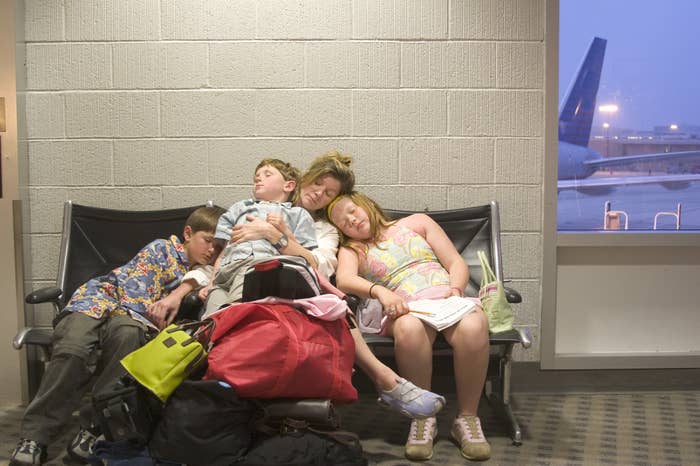 family sleeping in airport chairs