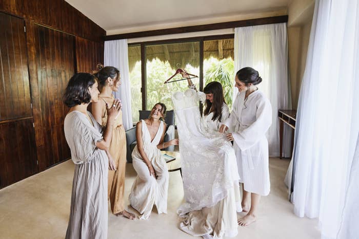A Bride holding a wedding dress surrounded by bridesmaids