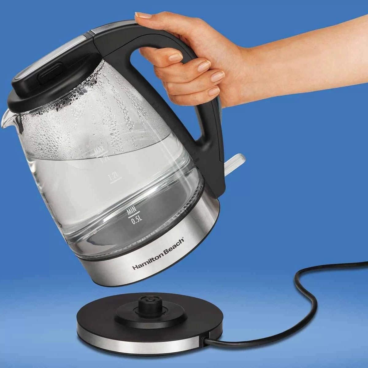 a person holding an electric kettle with hot water inside