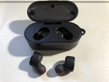 Reviewer image of two black earbuds next to their charging case