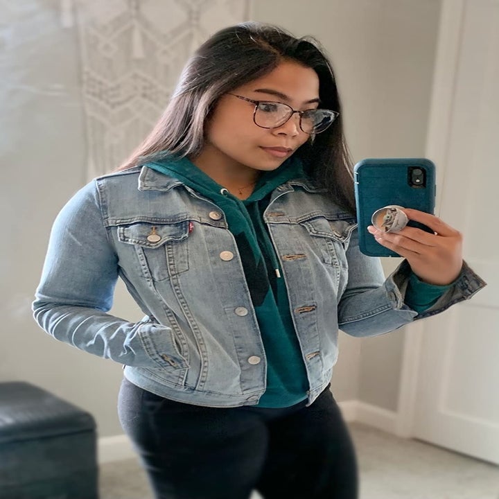 reviewer wearing the denim jacket over a green hoodie
