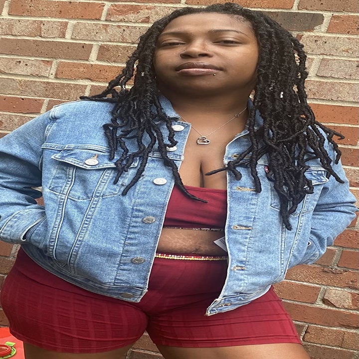 reviewer wearing the denim jacket over a red crop top and shorts