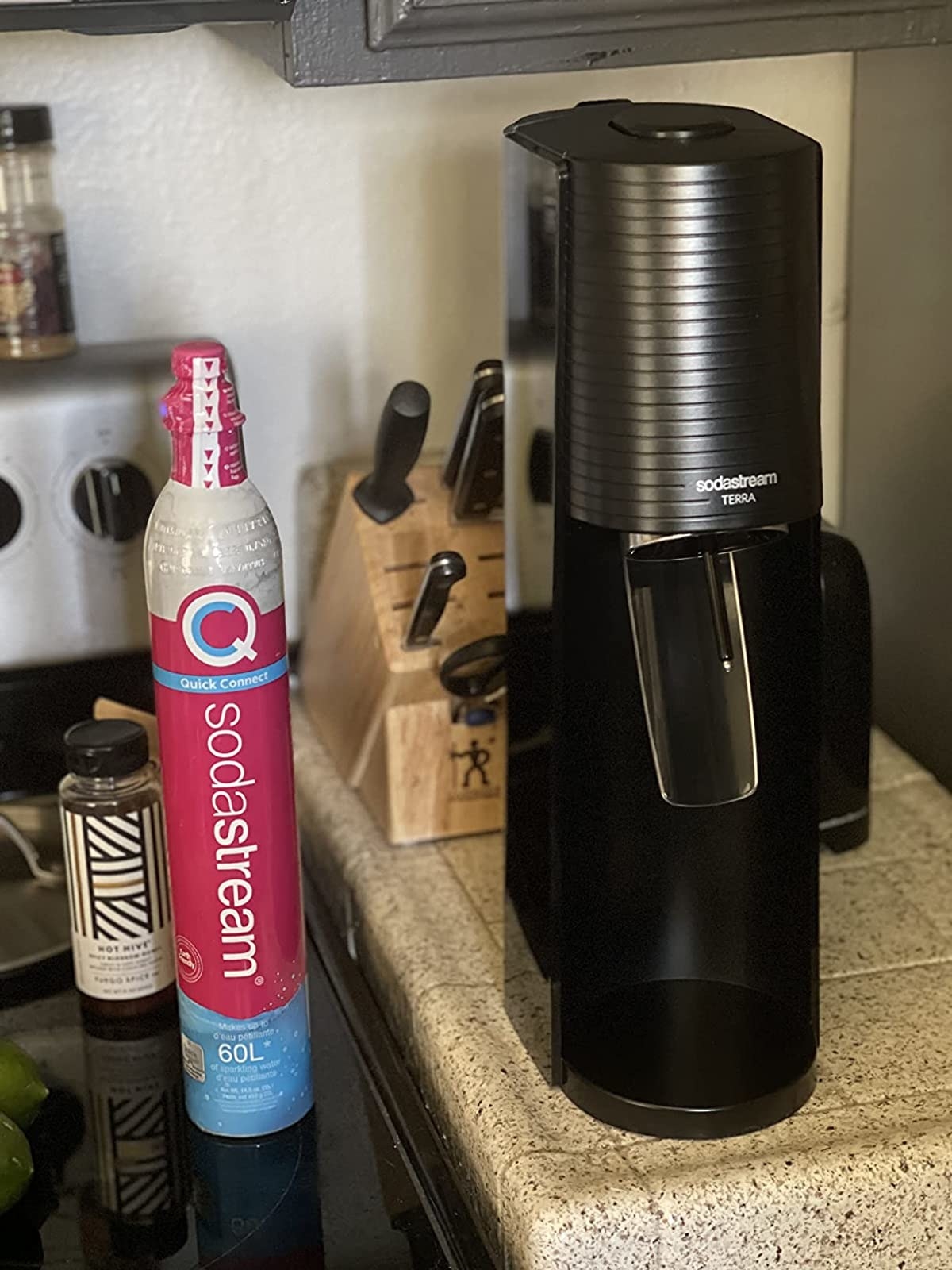 a reviewer&#x27;s black soda machine next to a bottle of CO2