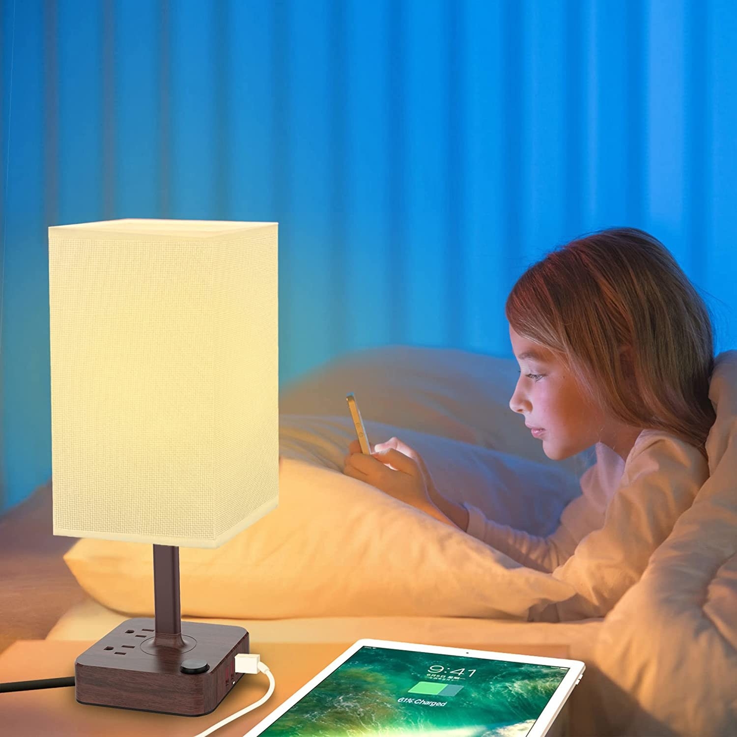 A girl in bed on her phone with a lamp on the bedside table beside her
