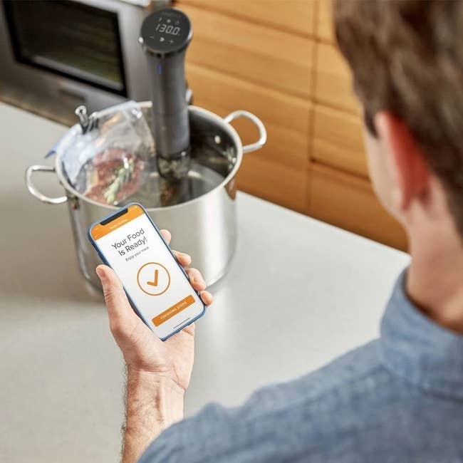 a model standing next to the sous vide with the accompanying phone app open
