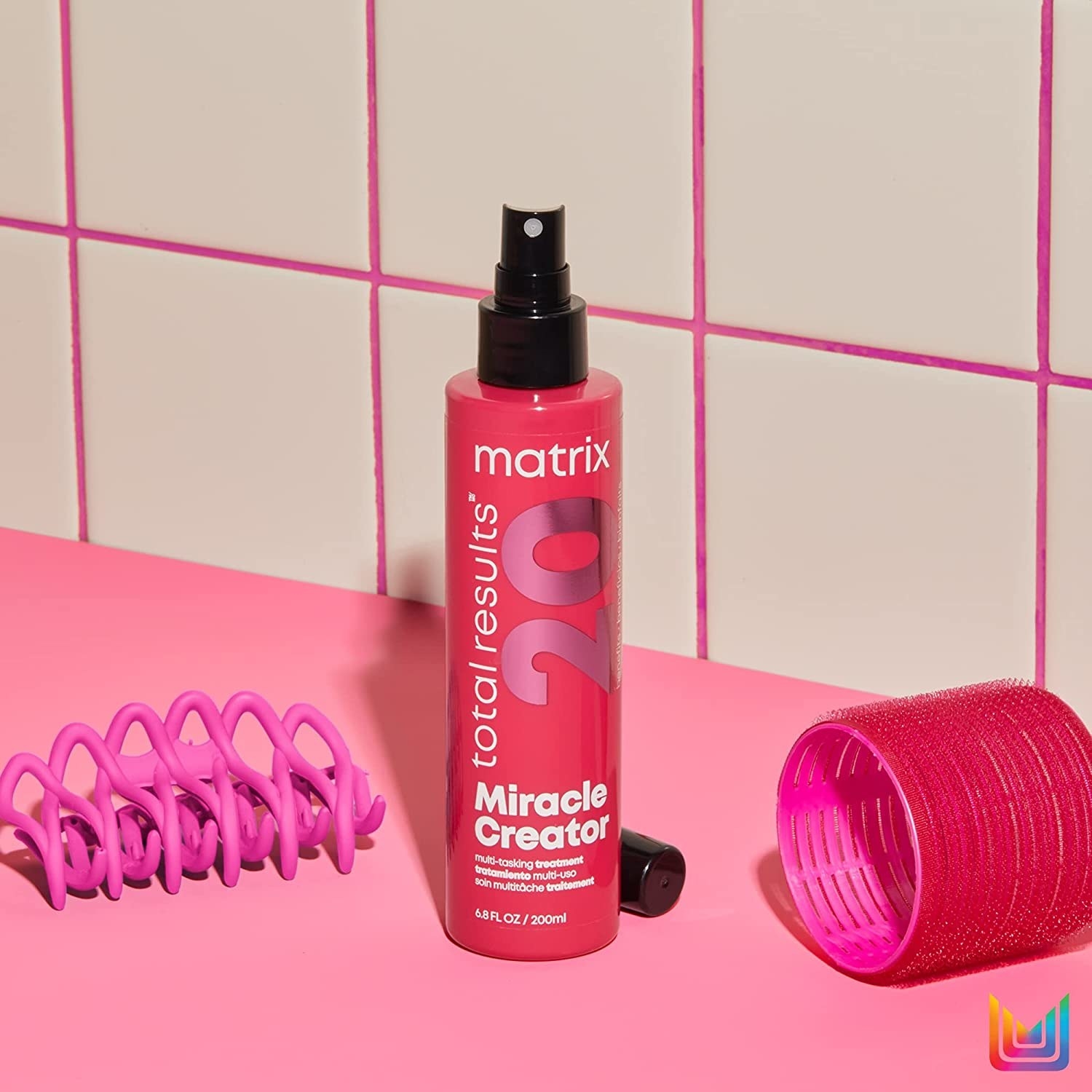 a bottle of the hair styling treatment next to hot rollers and a hair clip