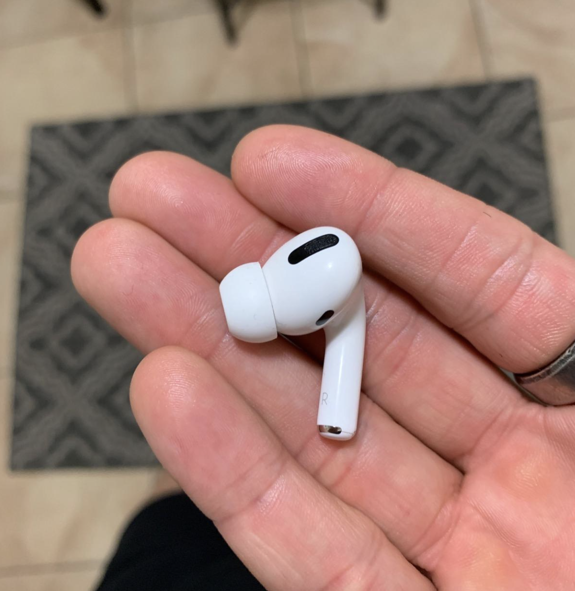 Reviewer holding a single AirPod