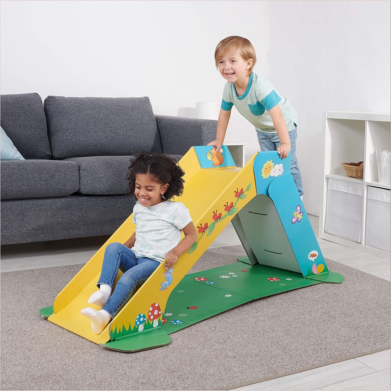 two toddlers playing on indoor cardboard slide