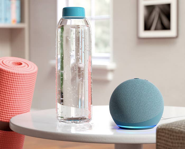 blue Echo Dot on table next to glass water bottle and yoga mat