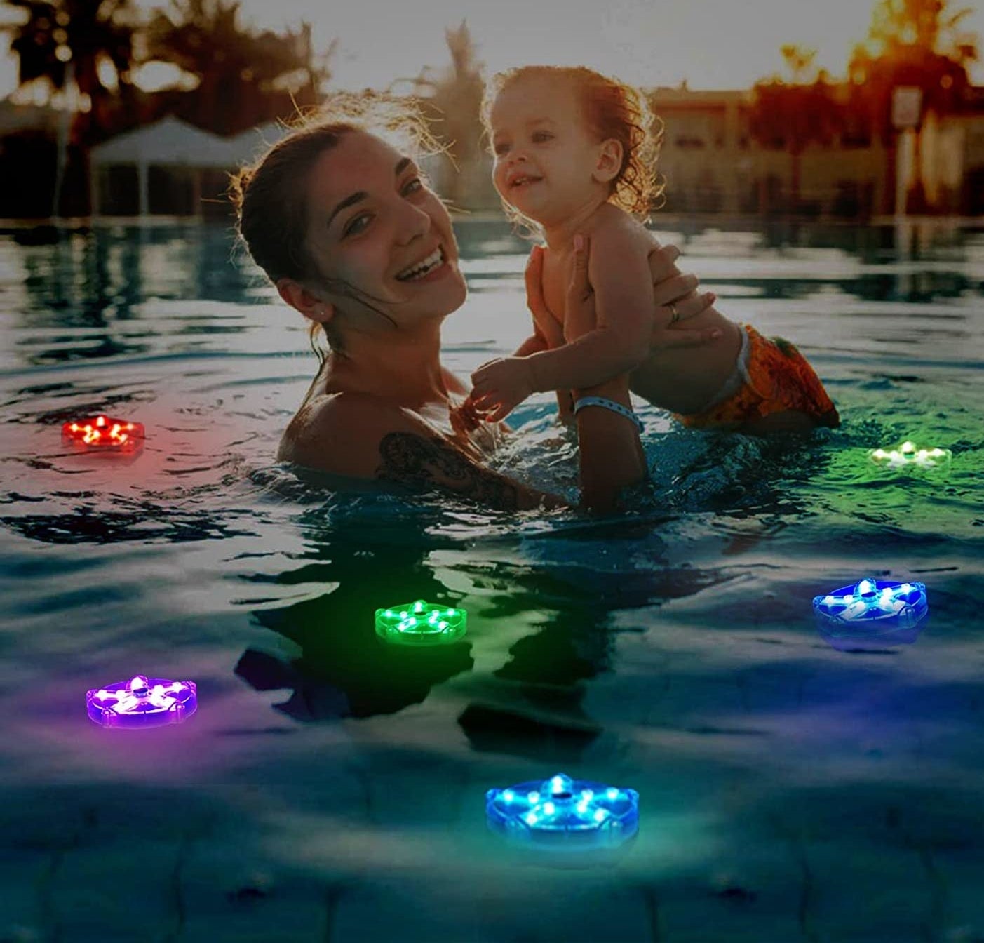 a person holding a baby in a lit-up pool