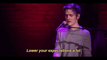 Bo Burnham singing &quot;Lower your expectations a lot&quot; while playing a piano