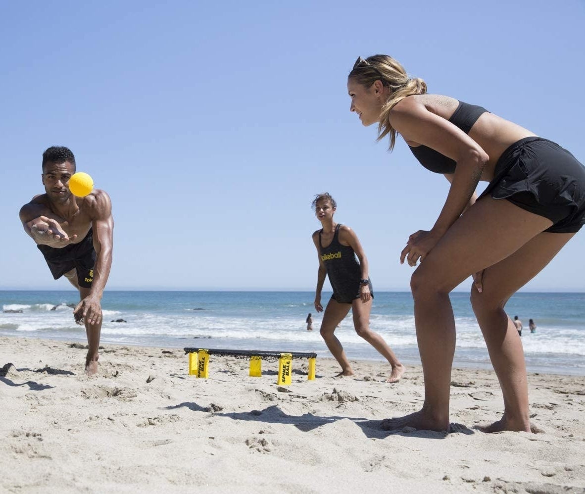 people playing spike ball on a beach