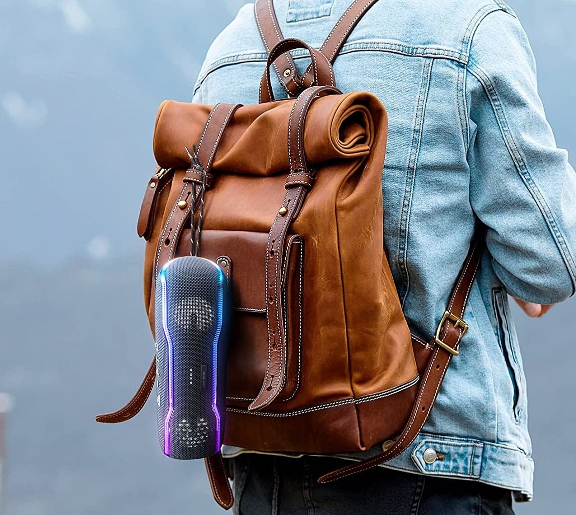model with rainbow glowing bluetooth speaker clipped onto backpack