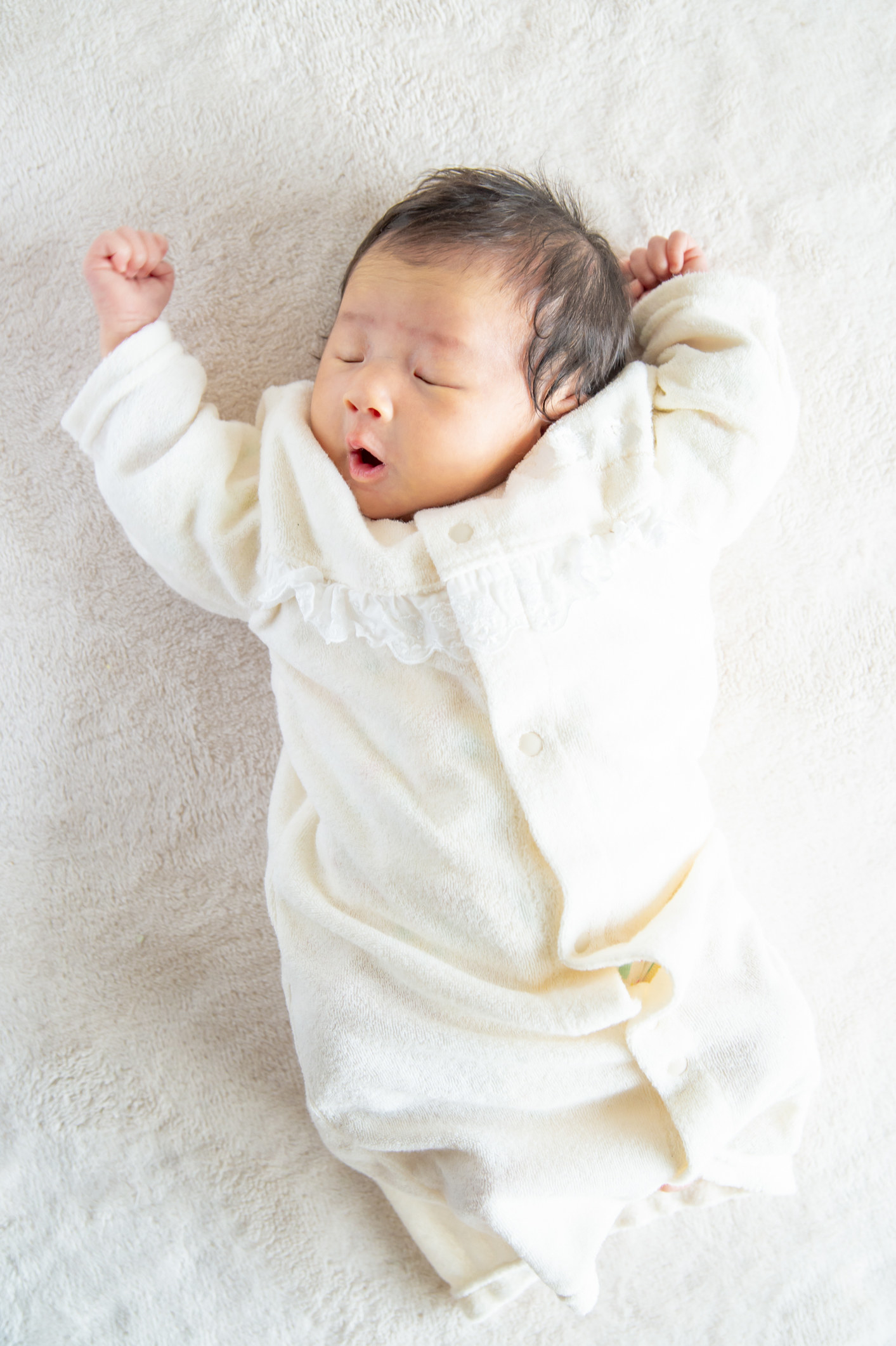 A newborn baby stretching her arms.