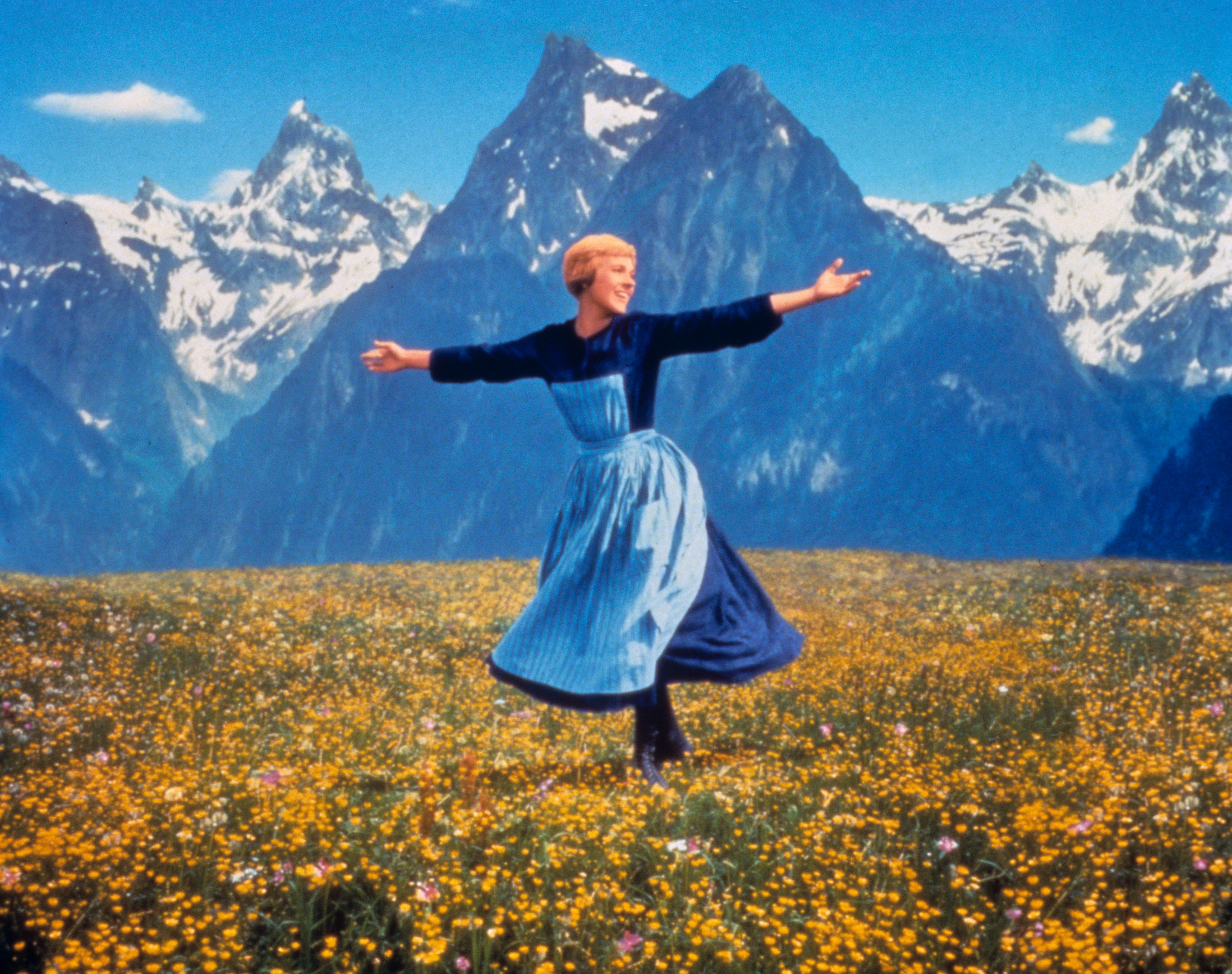A woman on a mountain top spins in a field