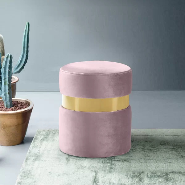 Blush pink ottoman with gold-wrapped center on area rug